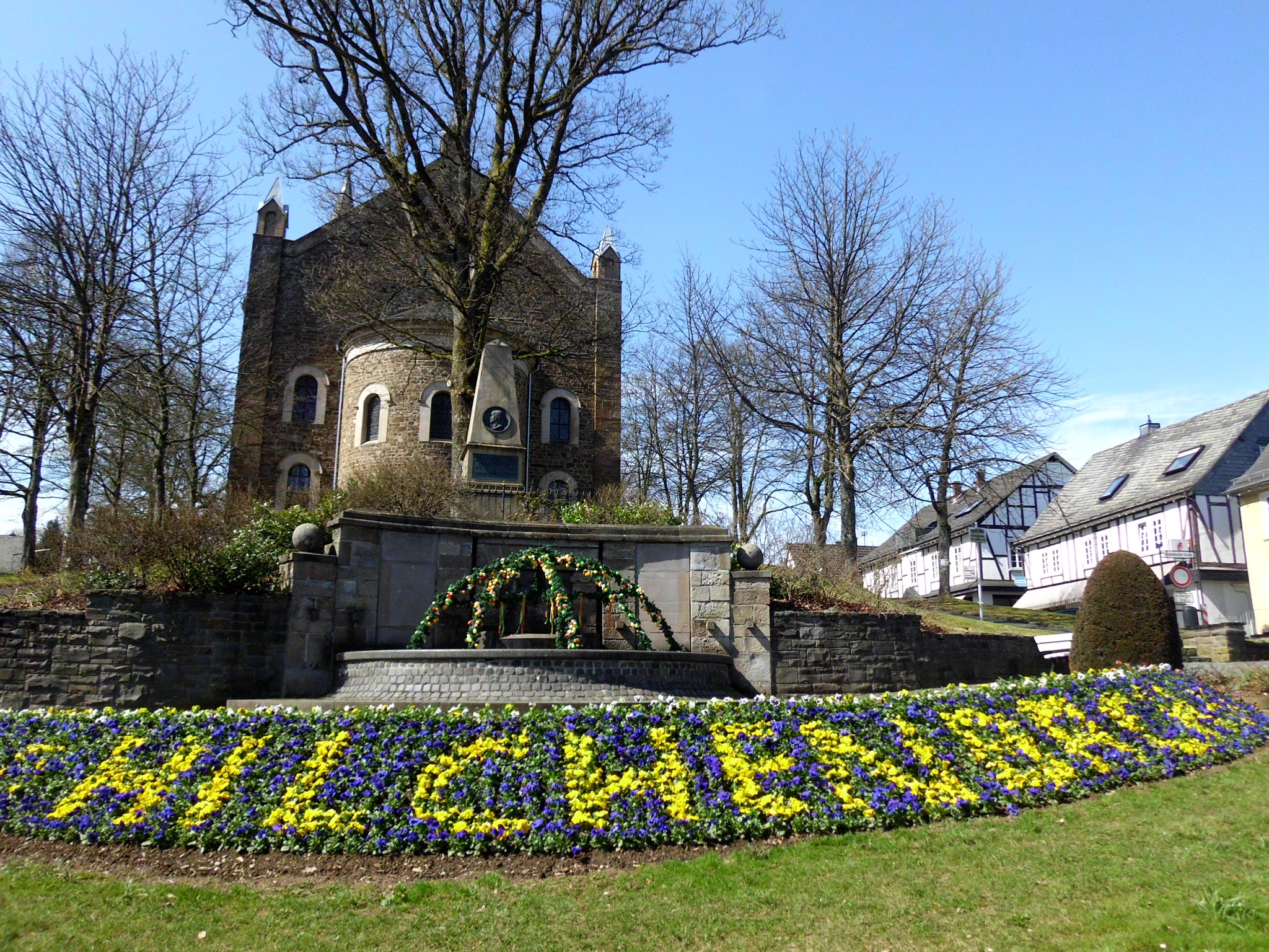 Ev. Kirche von Hilchenbach mit Jung Stilling Denkmal und Bepflanzung vor dem Brunnen. (Foto Susanne Träger)